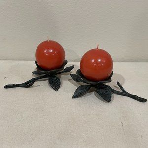 Two floral metal flower wrought iron candle holders with orange round candles